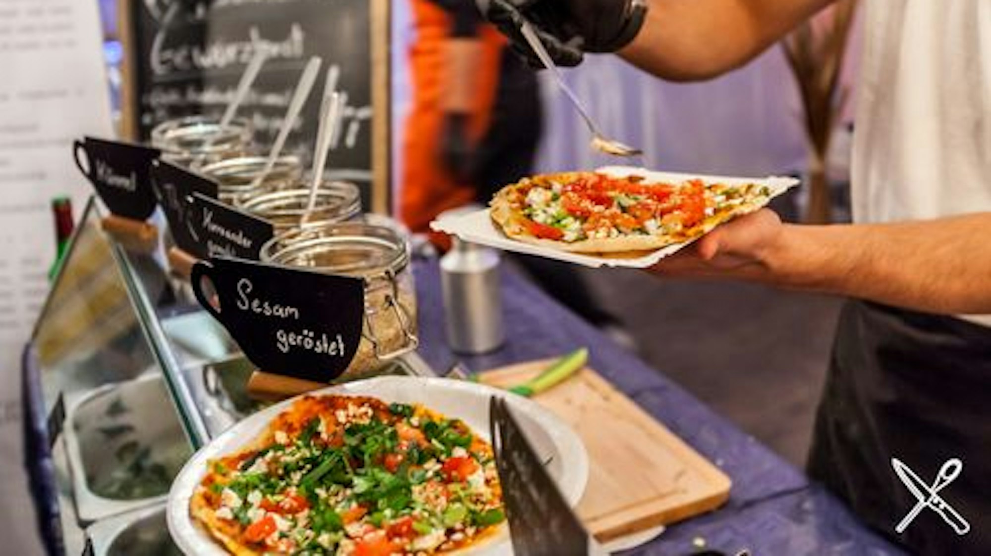 Eine Pizza wird mit Gewürzen und Öl bestreut.