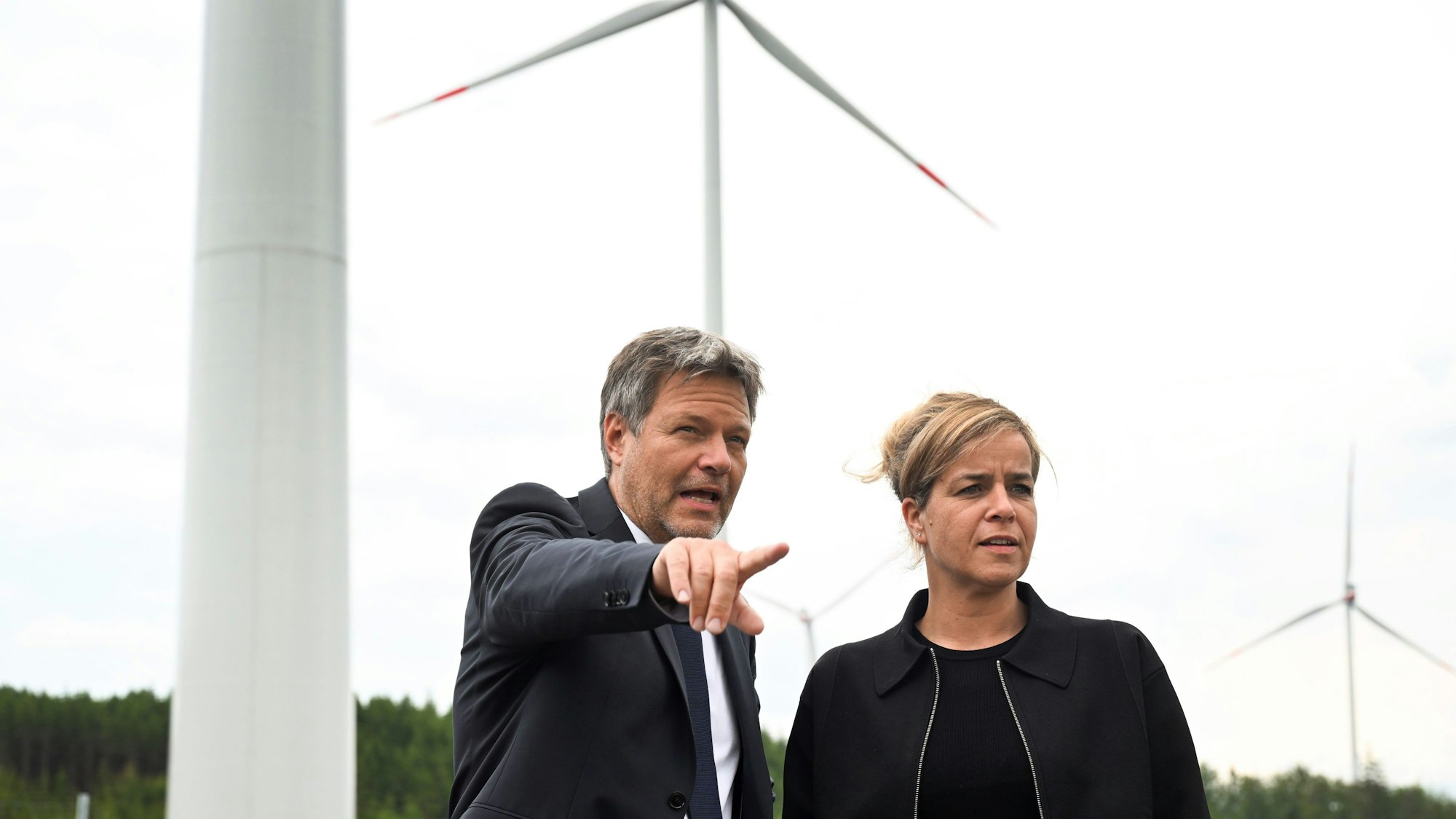Das Bild zeigt Robert Habeck (l), Bundeswirtschaftsminister, und NRW-Wirtschaftsministerin Mona Neubaur (beide Grüne), beide stehen vor Windrädern zur Stromerzeugung. Foto: Federico Gambarini/dpa +++ dpa-Bildfunk +++
