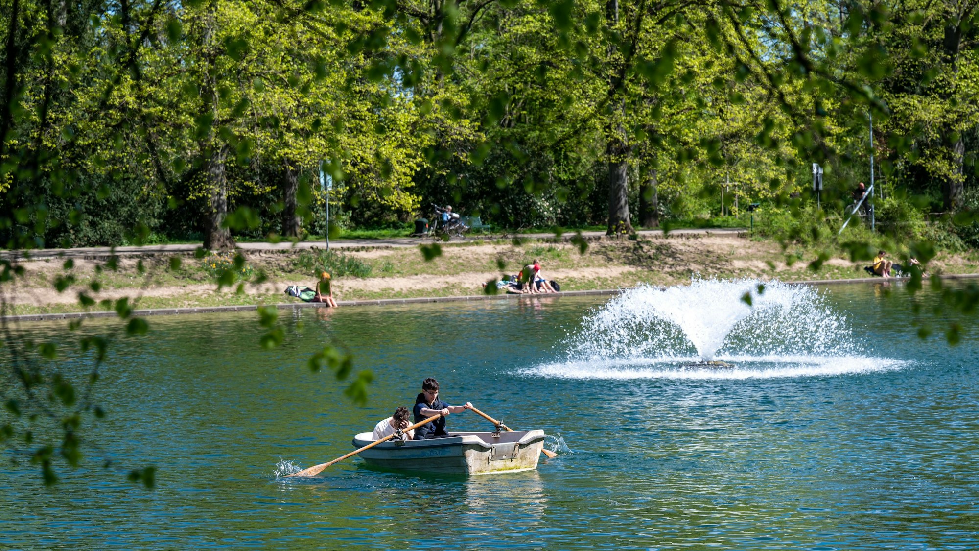 Zwei Personen fahren auf dem See im Blücherpark mit einem Ruderboot.
