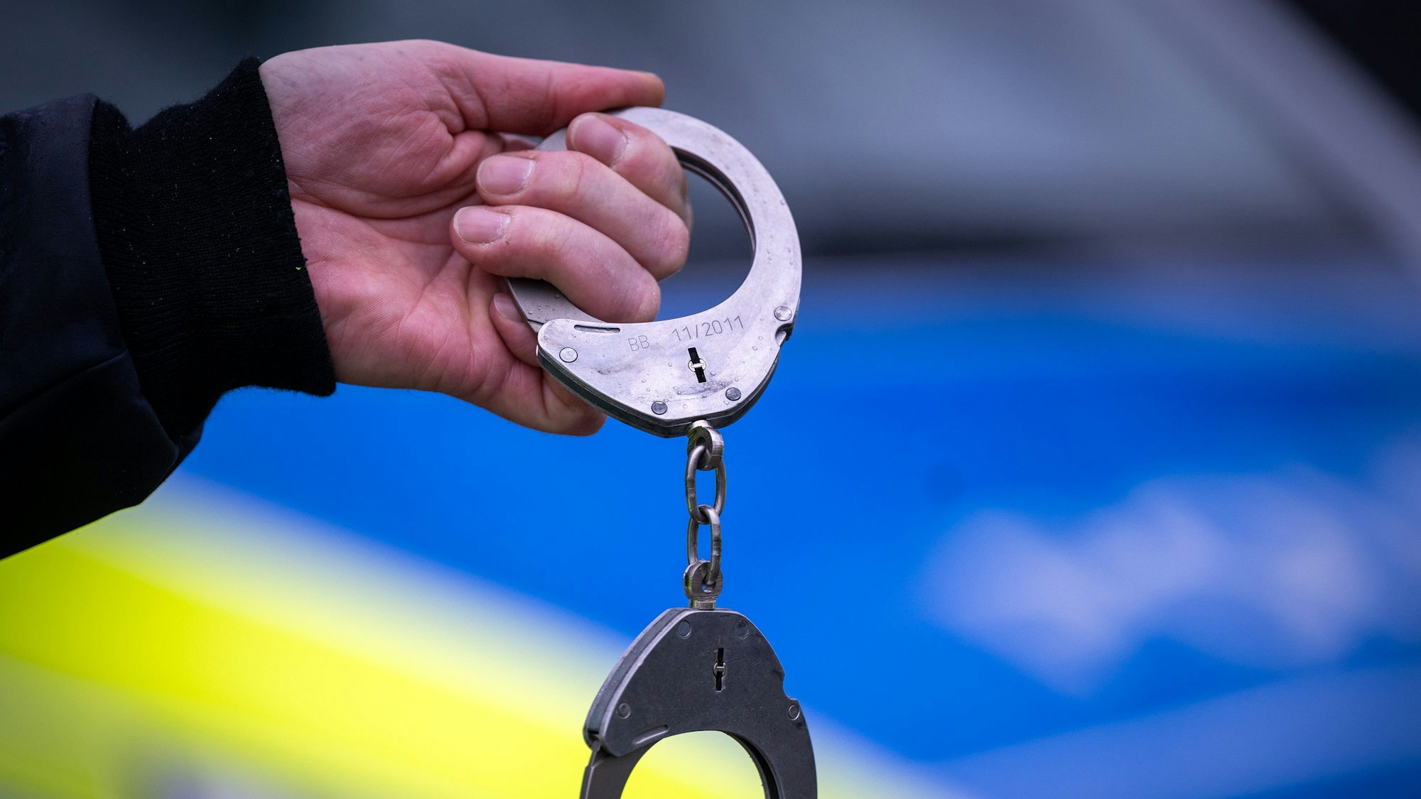 Ein Polizist hält während einer Verkehrskontrolle an der Berliner Straße ein Paar Handschellen.