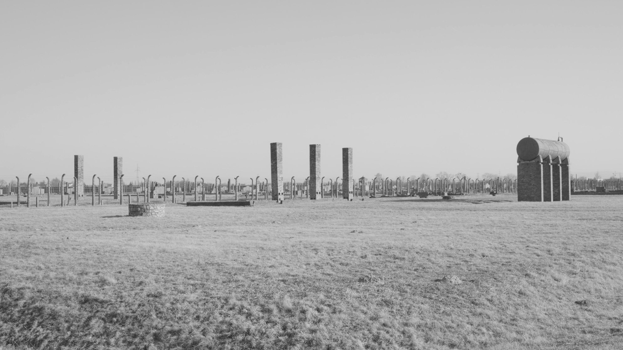 Ruinen des KZs Auschwitz-Birkenau stehen aus einem freien Feld.