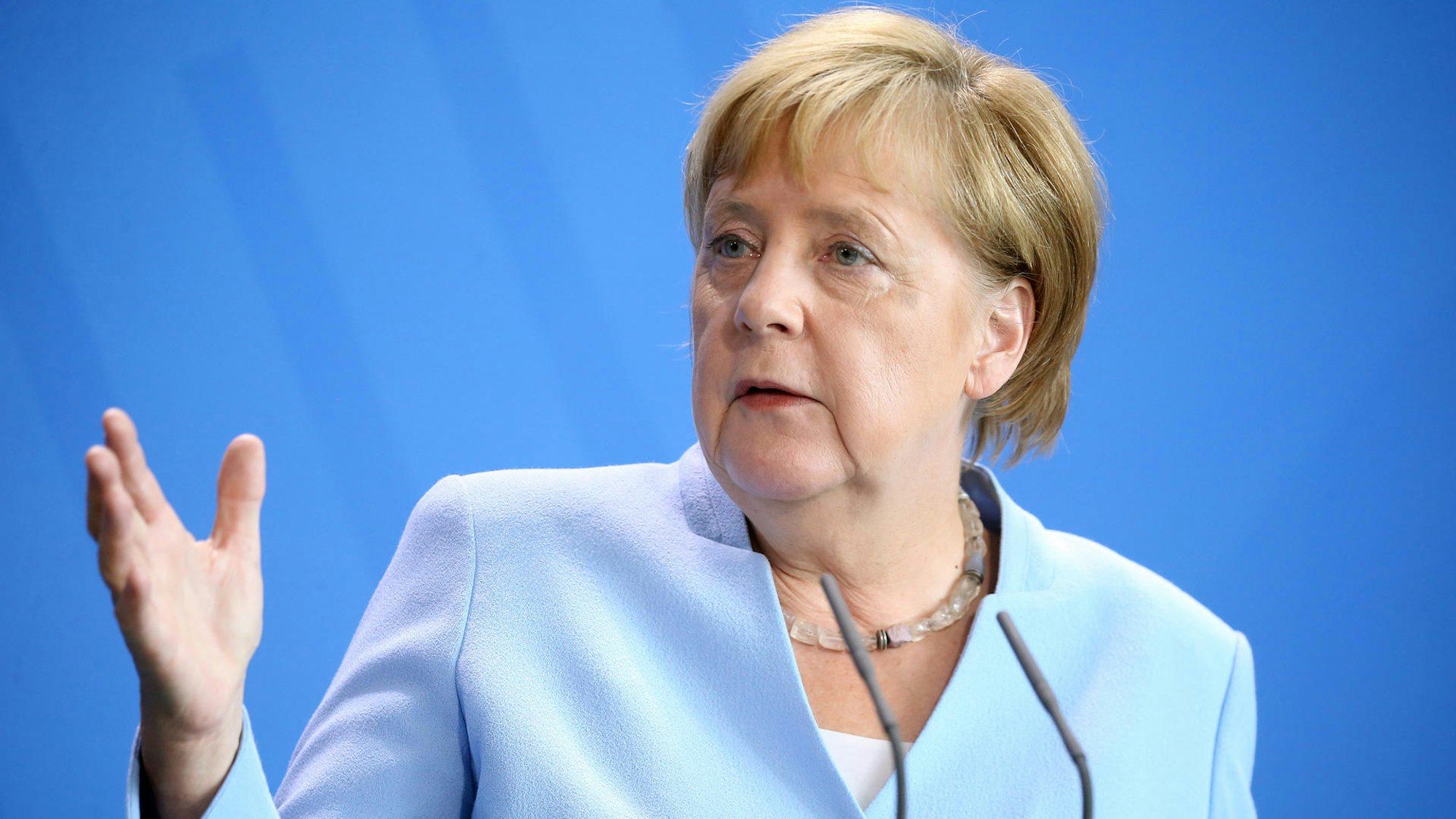 Angela Merkel hebt bei einer Rede die Hand.